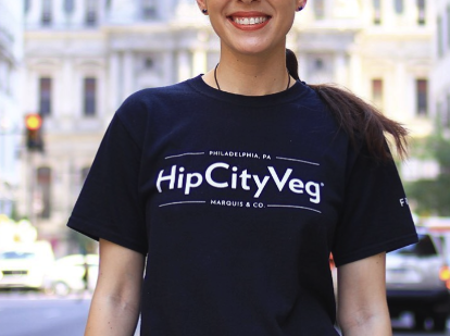 A HipCityVeg staff T-shirt worn on a Philadelphia street, printed with the HipCityVeg wordmark above the Marquis & Co. name.