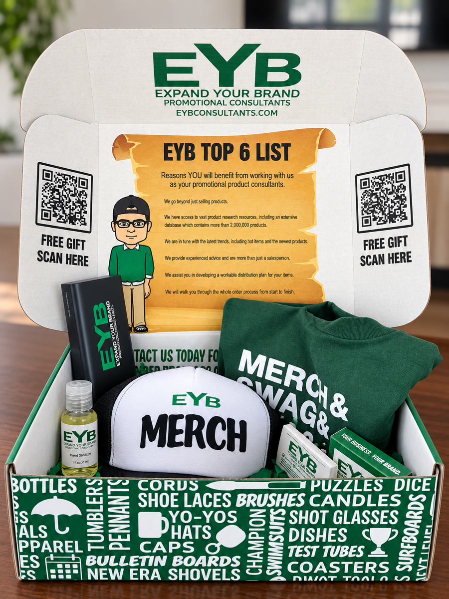 An open EYB gift box lined with green tissue, holding a branded quarter-zip, a MERCH trucker cap, a power bank, hand sanitizer and lip balm, with the EYB logo printed inside the lid.